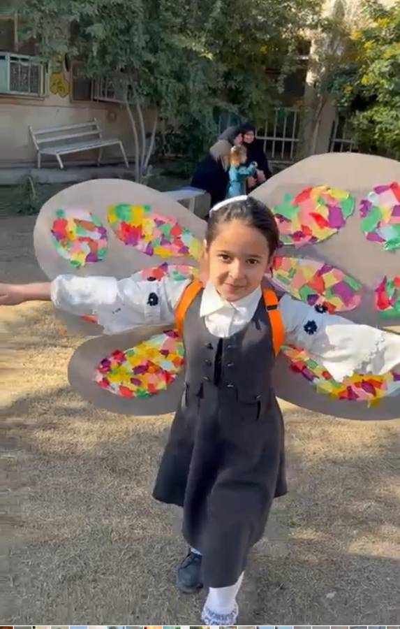 A girl wearing paper butterfly wings she made