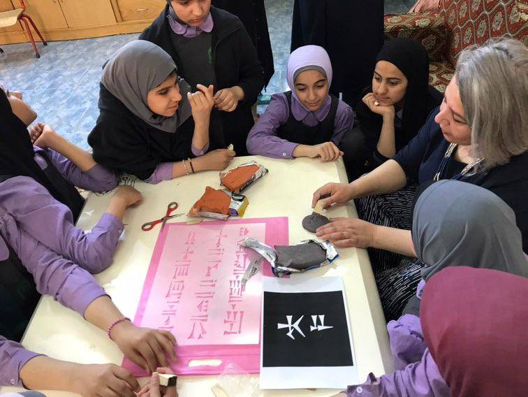 Girls tracing ancient cuneiform script in an art workshop